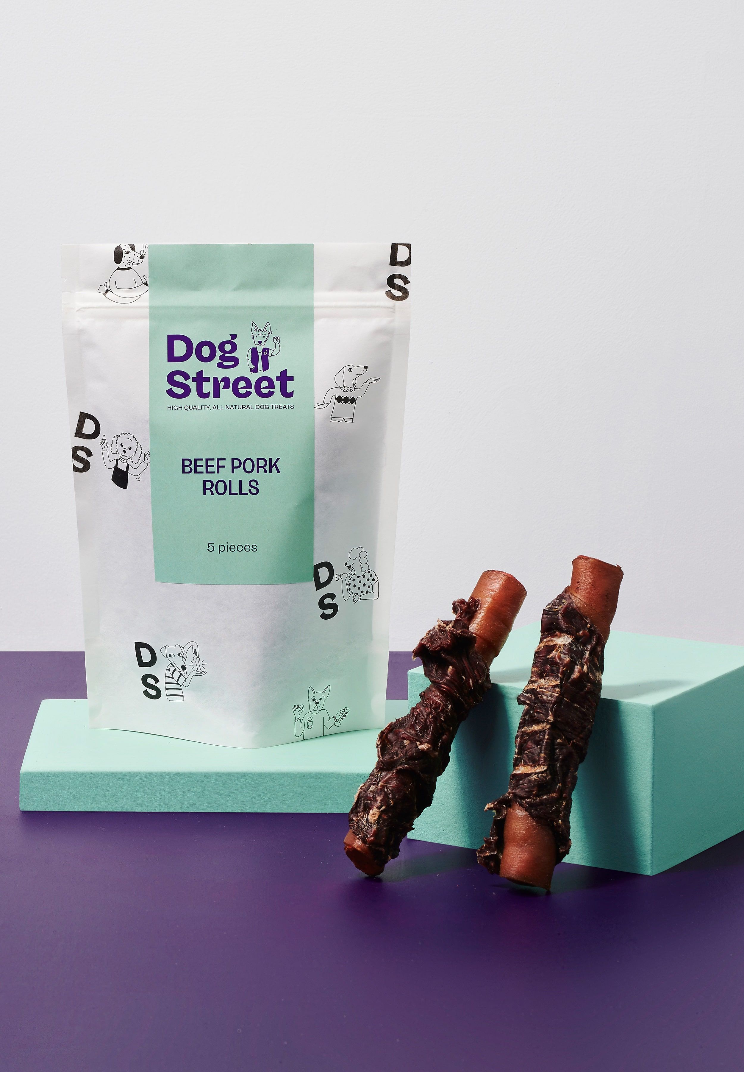 Styled shot of Dog Street Beef Pork Rolls pack and treats.