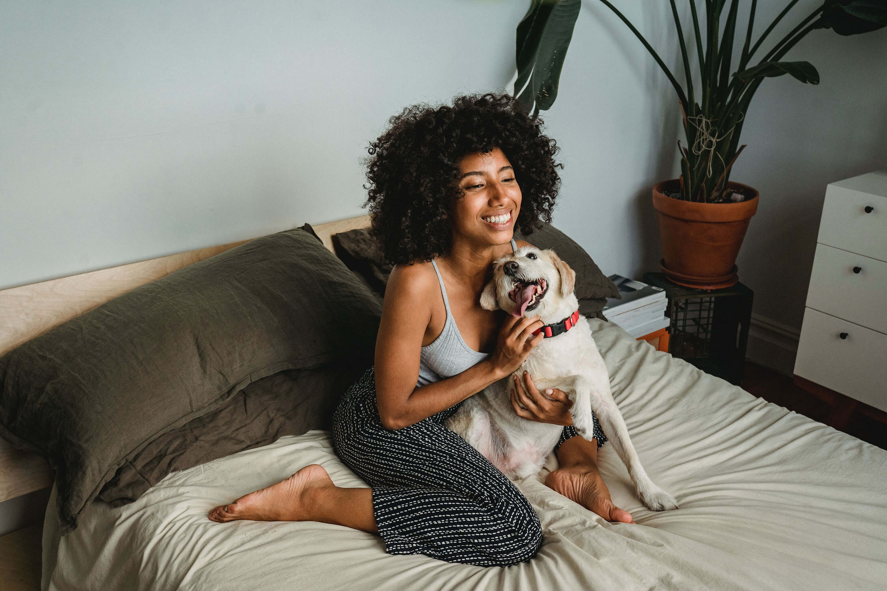 A woman cuddling a dog on a bed. 